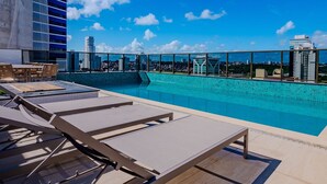 Una piscina sul tetto con poltrona relax e vista sulla città.