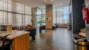Una moderna hall d'albergo con reception, zona relax e vista sull'esterno.