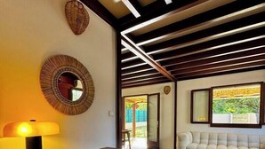 A modern living room with a wooden bench, a round mirror, and a sofa. - Charming Creole house - Private access to the beach (L'Étang-Salé)