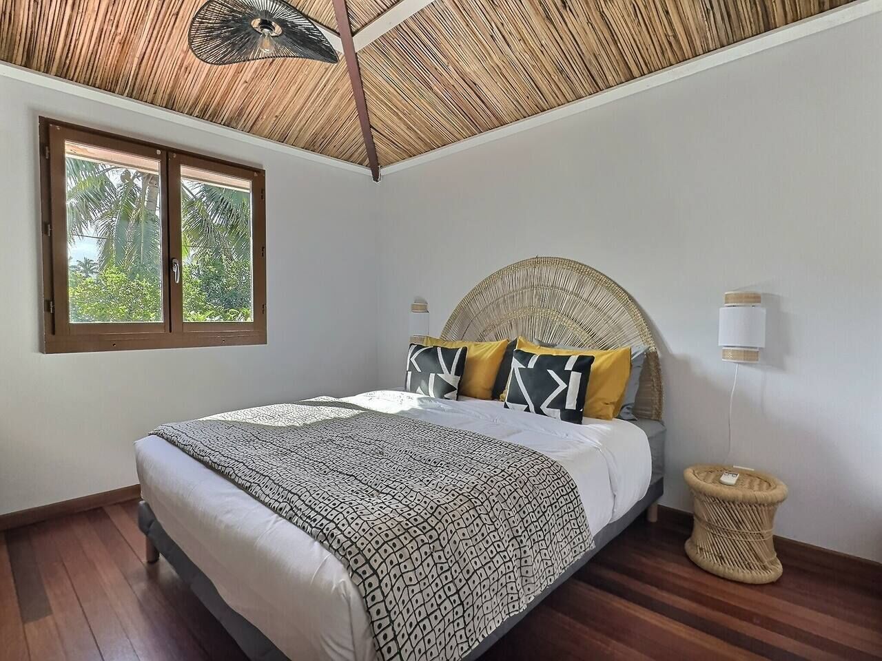 A bedroom with a bed, a window, a ceiling fan, and a bedside lamp.