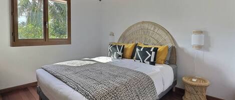 A bedroom with a bed, a window, a ceiling fan, and a bedside lamp.