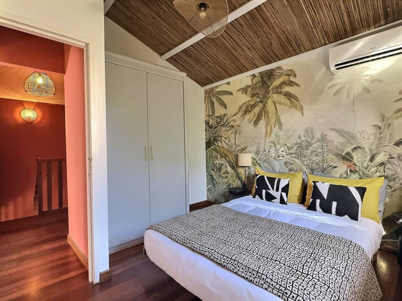 Ein Schlafzimmer mit Bett, Kleiderschrank, Deckenventilator und Wandgemälde.