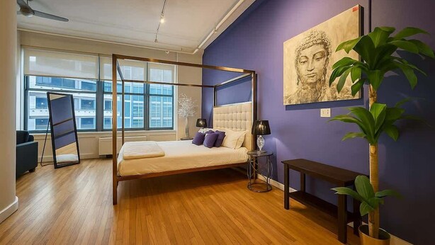 A modern bedroom with a four-poster bed, a large window, and a Buddha painting on the wall. - King Bed Studio Loft. Huge Beautiful Ceilings (Dallas)