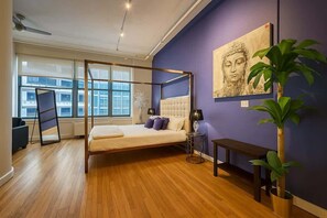 A modern bedroom with a four-poster bed, a large window, and a Buddha painting on the wall. - King Bed Studio Loft. Huge Beautiful Ceilings (Dallas)