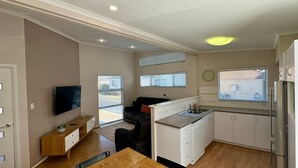 Un espace de vie compact comprenant un coin cuisine, un coin repas et un coin salon avec un canapé et un téléviseur.