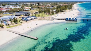 A coastal area with a beach, a pier, and a building with a blue roof.