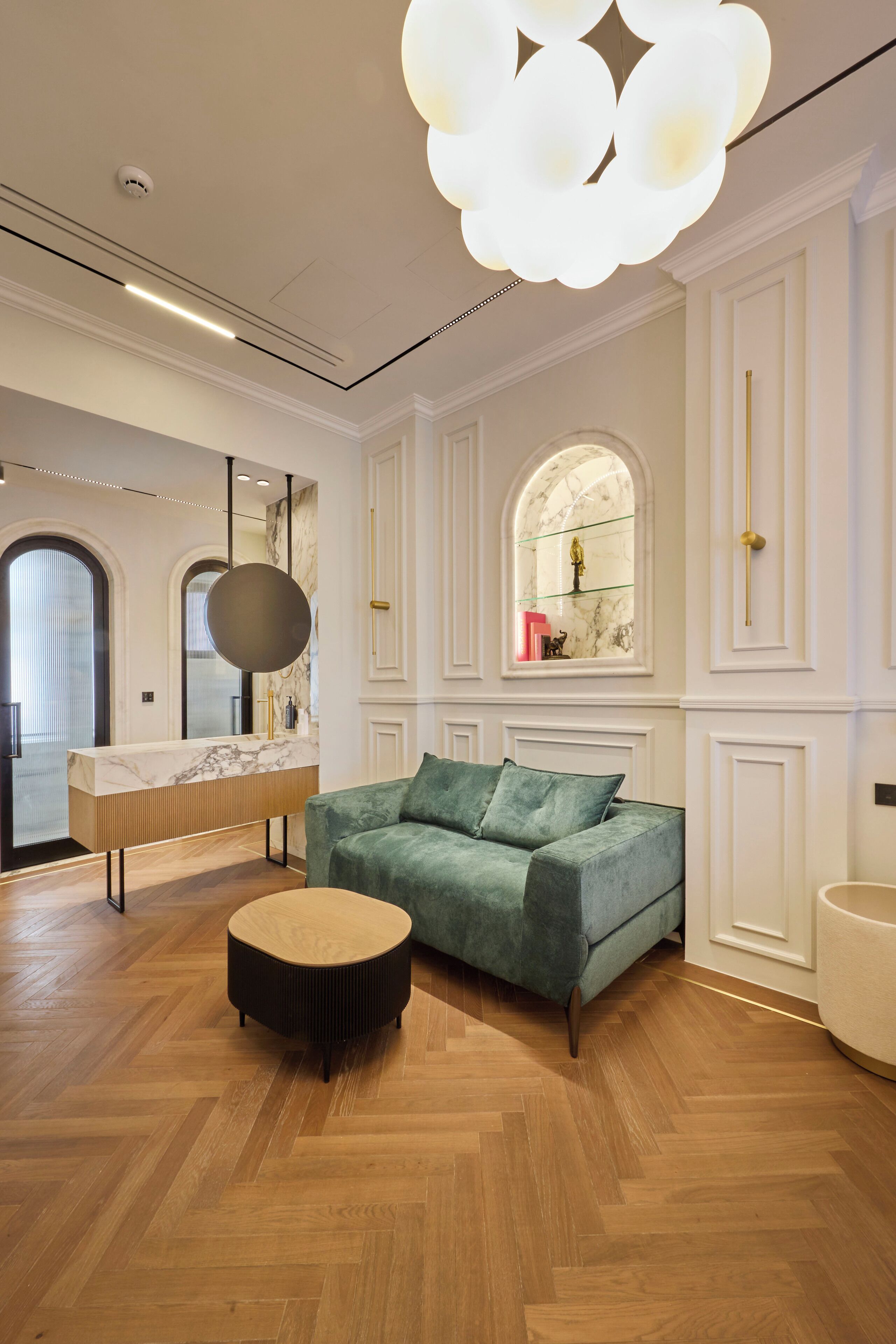 A modern interior with a marble vanity, a green sofa, and a unique ceiling light fixture.