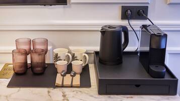 Una encimera de cocina con una cafetera, un hervidor y cuatro tazas.