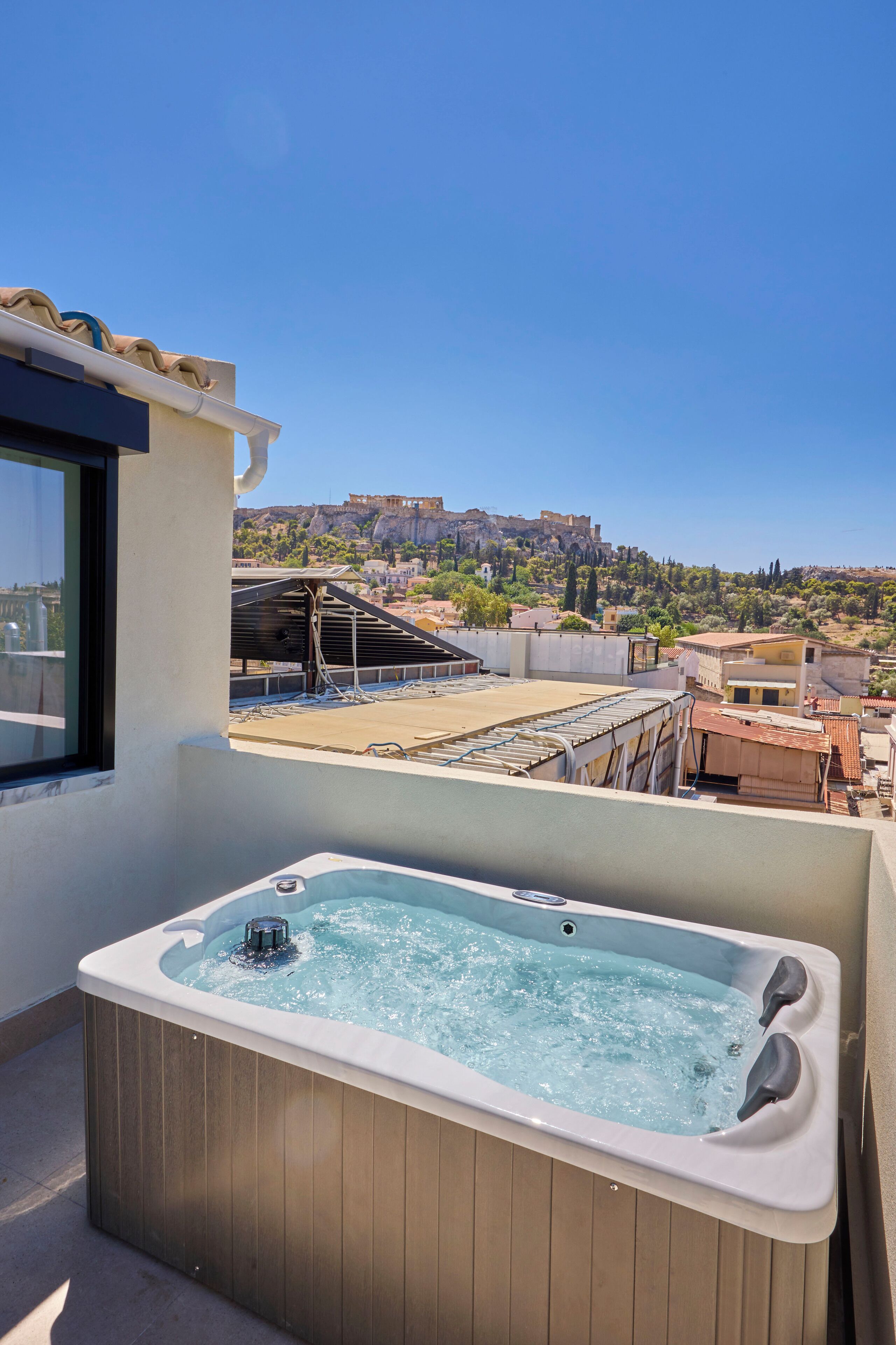 Un tetto con una vasca idromassaggio, vista su una città storica e cielo azzurro limpido.