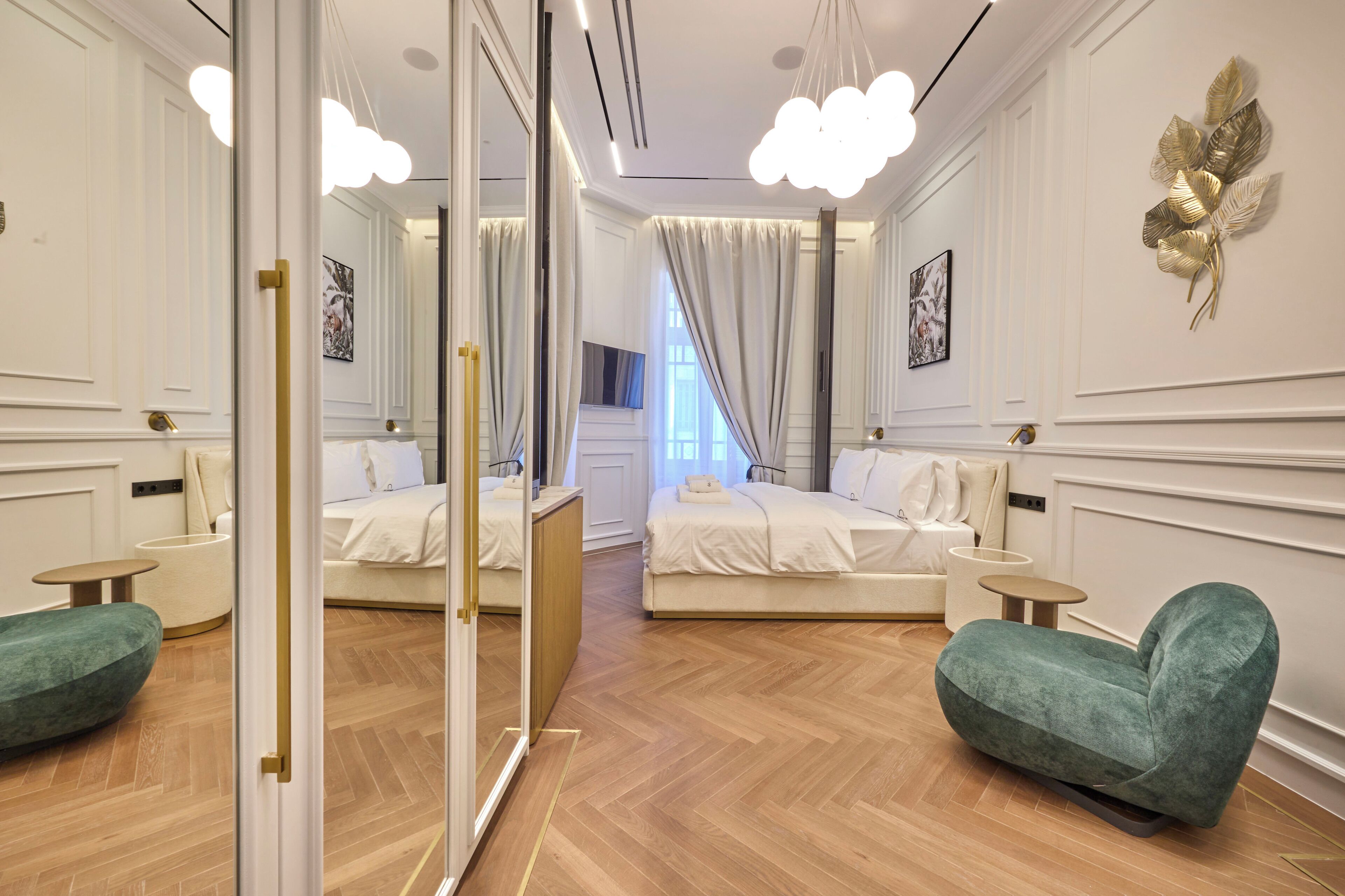 Una camera d'albergo con un armadio a specchio, un letto, una poltrona verde e un tavolino.