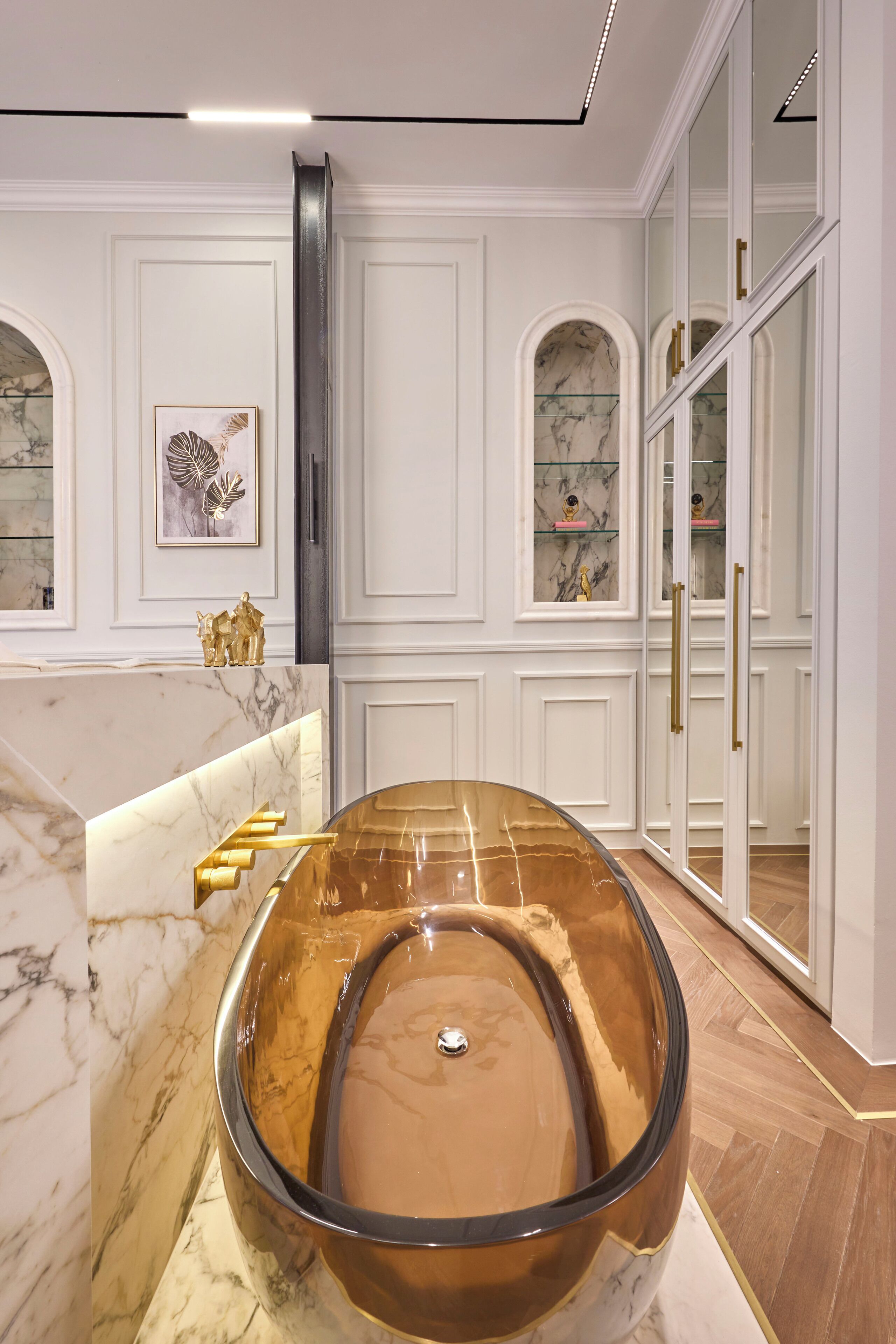 A luxurious bathroom with a large oval bathtub, marble countertops, and a glass-enclosed vanity.