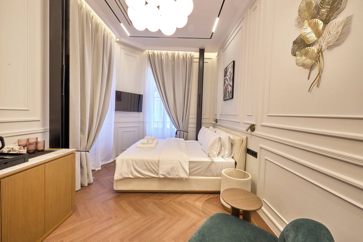 A hotel room with a bed, a bedside table, a chair, and a view of the hallway.