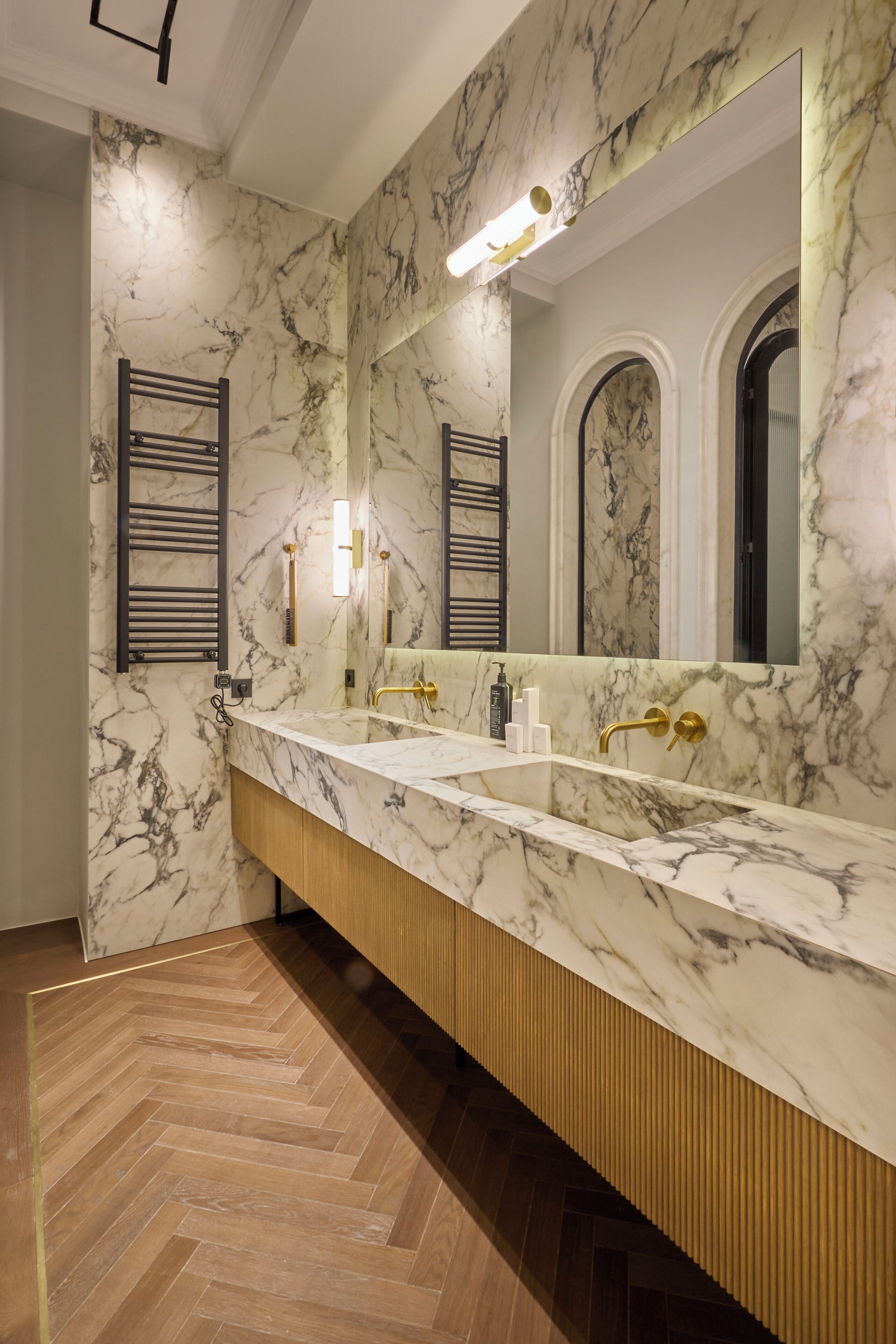 Un baño moderno con tocador de mármol, lavamanos dobles y un espejo grande.