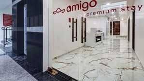 Eine moderne Hotelhalle mit Marmorboden, Glastüren und einem Schild mit der Aufschrift 'amigo premium stay'.