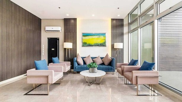 Een moderne lobby met een blauwe zithoek, een bijzettafeltje en een schilderij aan de muur.