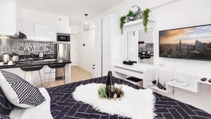 Een modern appartement met een keuken, een eethoek en een woonkamer met een grote televisie.