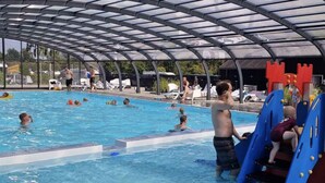 A swimming pool with a transparent roof, surrounded by lounge chairs and a castle-like structure.