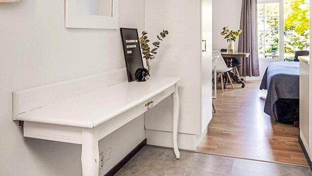 A modern room with a white desk, a small table with chairs, a bed, and a view of greenery outside. - 2 Person Holiday Park Home in Bastad (Bastad)