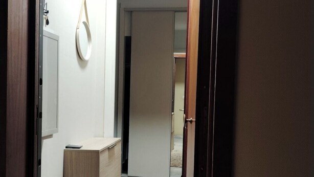 Ein Korridor mit einem Holzkabinett, einem Spiegel und einem Hut an der Wand.