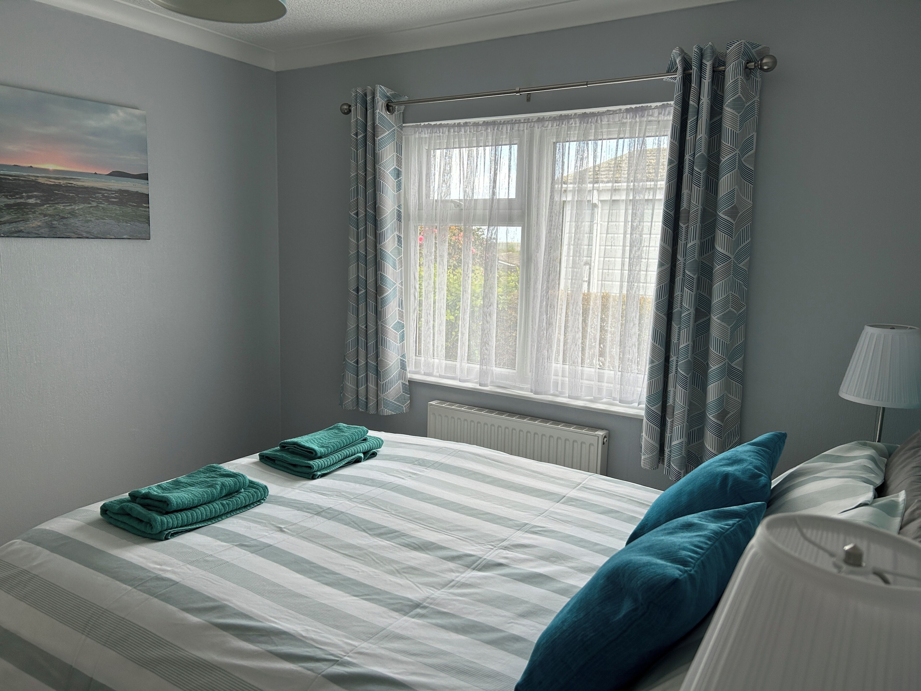 Une chambre à coucher avec un lit, un radiateur, une fenêtre avec des rideaux et une lampe.