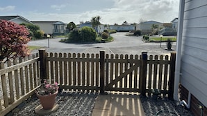 A gated driveway leading to a residential area with houses and a clear sky.