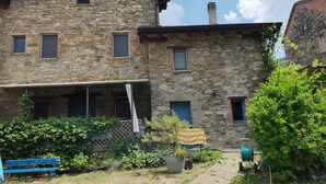 A stone building with multiple windows and a covered porch area.