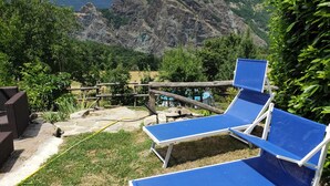 A patio area with blue lounge chairs and a wooden fence, overlooking a mountainous landscape.