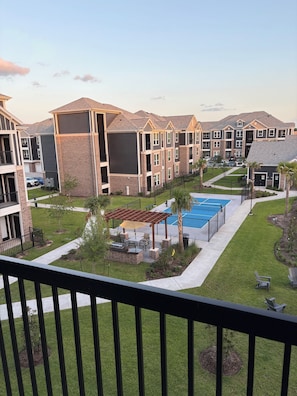 A residential complex with multiple apartment buildings, a tennis court, and a small patio area with outdoor seating. - Charming 2-bedroom apartment with WiFi in Spring (Spring)
