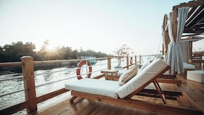 Un muelle de madera con una tumbona y un flotador salvavidas, con vistas a un cuerpo de agua.