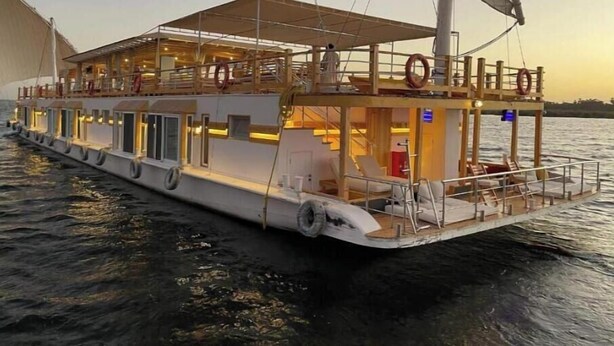 Un velero grande de varias cubiertas con una cubierta superior protegida y una cubierta inferior con asientos y zona de bar.