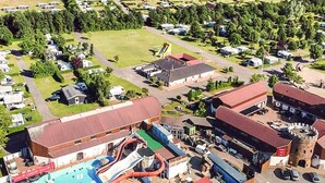 Vue aérienne d’un terrain de camping avec des camping-cars, une piscine et un toboggan aquatique.