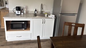 Uma cozinha compacta com micro-ondas, pia e geladeira.