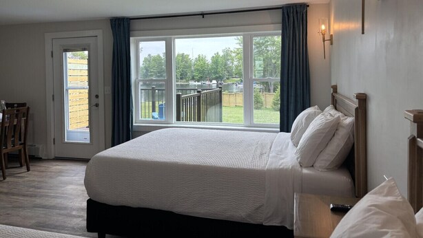 Quarto com uma cama grande, vista para um lago e porta que dá para uma varanda.