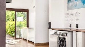 Eine moderne Küche mit integriertem Waschtrott und Trockner, einer Glastür zum Garten und einer an der Wand befestigten Infotafel.
