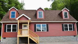 A two-story house with a front porch, a staircase leading to the entrance, and a small deck area.