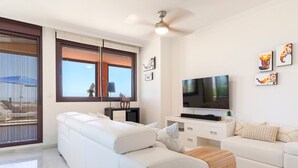 A modern living room with a white sofa, a TV, and artwork on the wall.