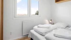 A bedroom with two beds, a window, and a radiator.