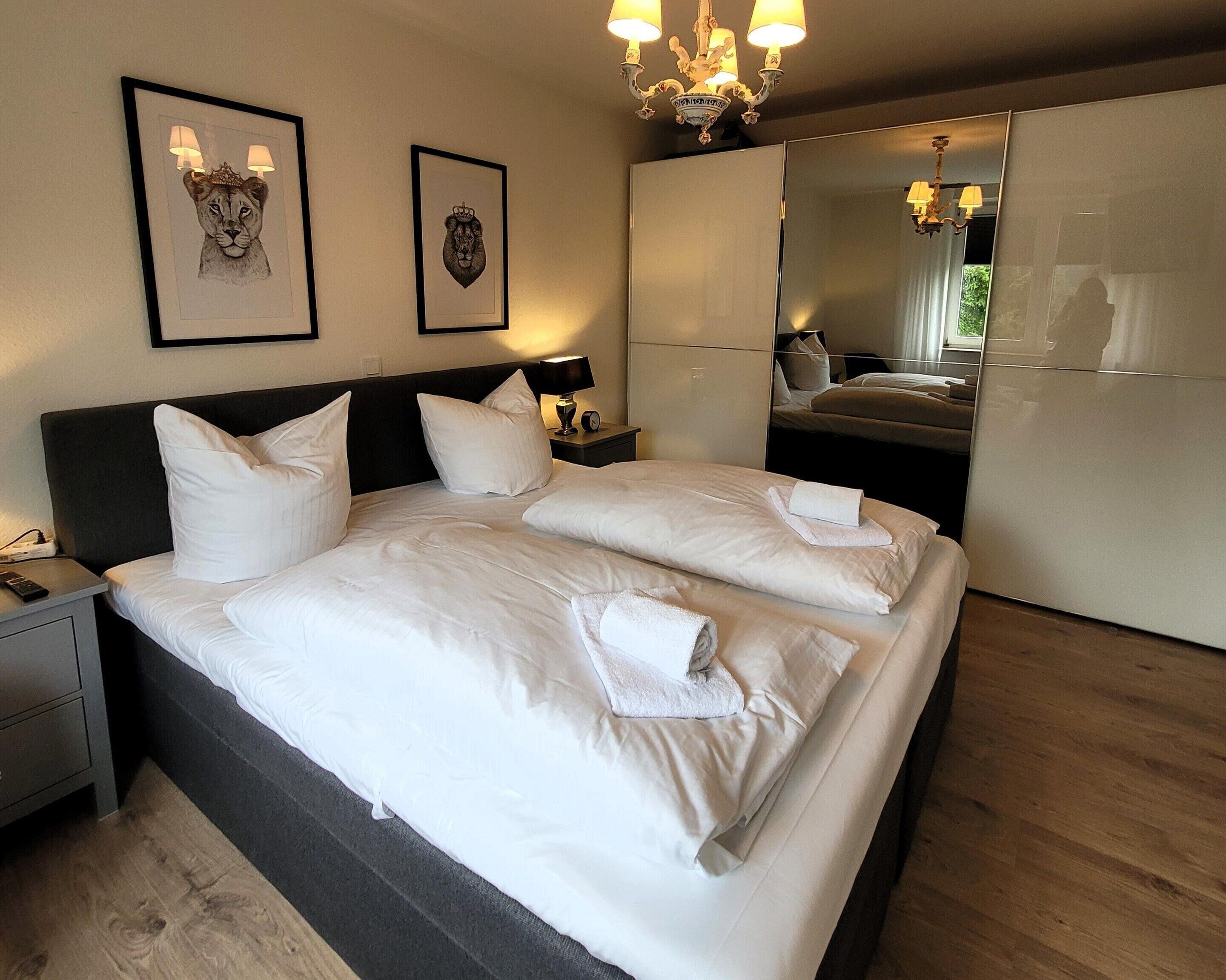 A hotel room with a large bed, two nightstands, a mirror, and artwork on the wall.