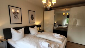 A hotel room with a large bed, two nightstands, a mirror, and artwork on the wall. - Apartment in the Centre of Winterberg (Winterberg)