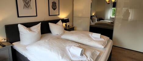 A hotel room with a large bed, two nightstands, a mirror, and artwork on the wall.
