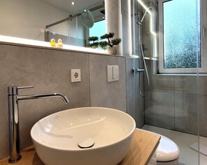 A modern bathroom with a large vessel sink, a handheld showerhead, and a glass-enclosed shower. - Apartment in the Centre of Winterberg (Winterberg)