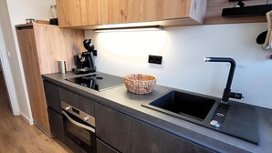 A modern kitchen with a black countertop, stainless steel appliances, a built-in sink, and wooden cabinets. - Apartment in the Centre of Winterberg (Winterberg)
