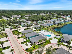 An aerial view of a residential area with houses, a swimming pool, and a lake.