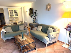 Ein Wohnzimmer mit zwei Sofas, einem Couchtisch, einer Vitrine, einer Lampe und einem Wandbild.