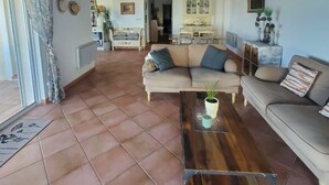 A spacious living room with a high ceiling, a large sofa set, a coffee table, and a cabinet with glass doors. - MAGNIFICENT VILLA SEA VIEW 4 BEDROOMS SWIMMING POOL QUIET ON THE HEIGHTS OF BORMES (Bormes-les-Mimosas)