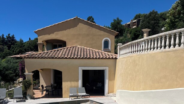 A swimming pool with a tiled deck, a beige building with a tiled roof, and a white balustrade. - MAGNIFICENT VILLA SEA VIEW 4 BEDROOMS SWIMMING POOL QUIET ON THE HEIGHTS OF BORMES (Bormes-les-Mimosas)