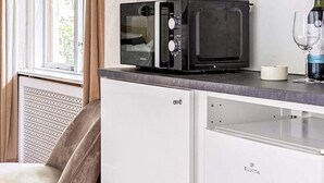 A compact kitchenette with a microwave on a countertop, a white cabinet below, and a chair in the background. - 3 Person Holiday Park Home in Bastad (Bastad)