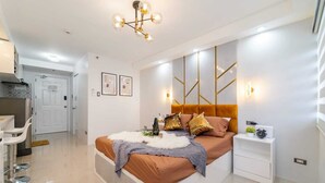A modern bedroom with a large bed, bedside tables, a desk, and a chair. - Infini by J&J ( City Center |Near Malls ) (Cebu City)