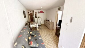 A compact living space with a sofa, dining table, and kitchenette.