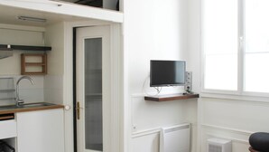 A compact kitchen with a built-in oven, a white refrigerator, and a small window. - Nice studio with Wifi near Montparnasse (Paris)